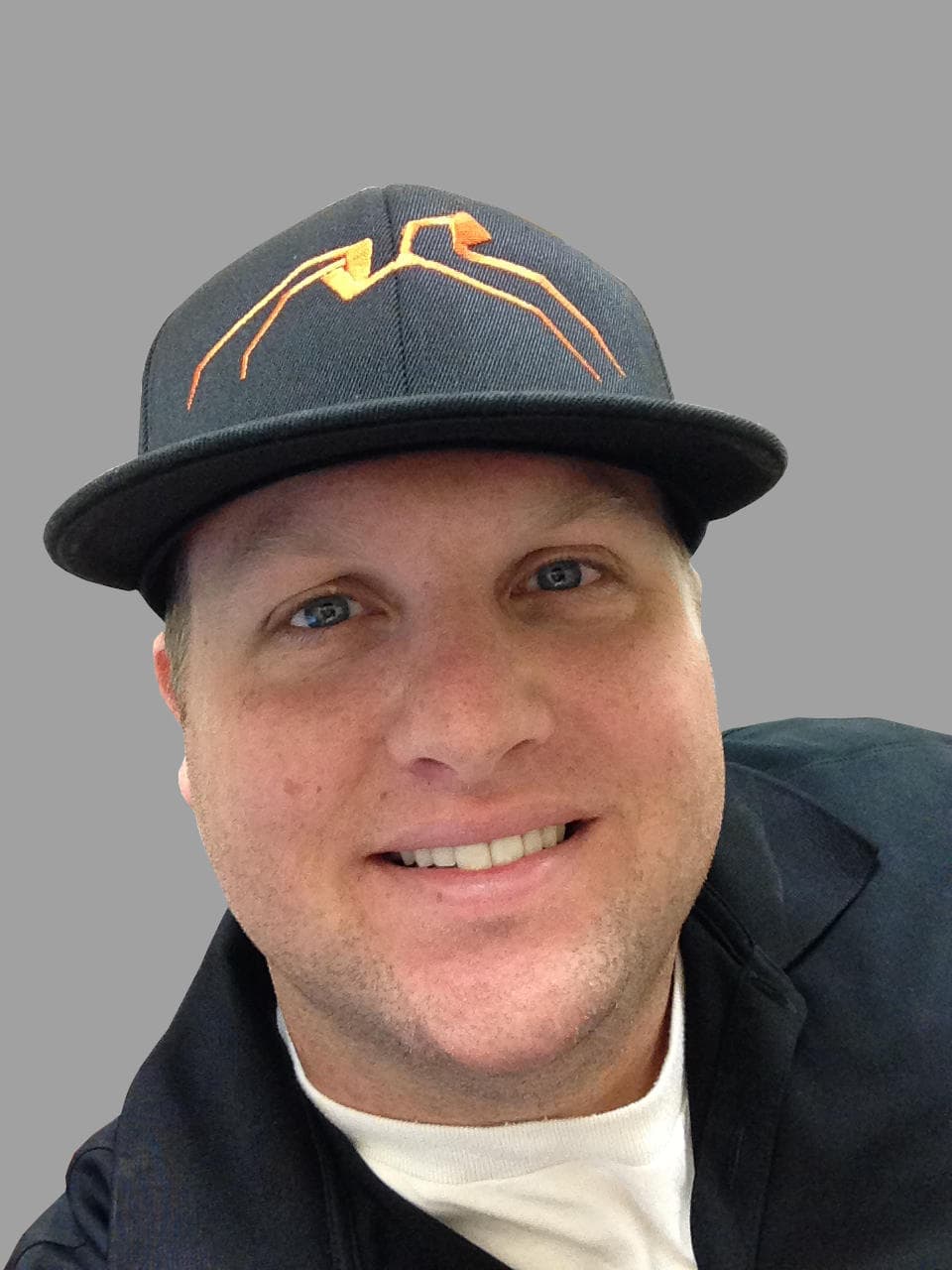 Stampede team member smiling in a branded company hat and dark collared shirt.